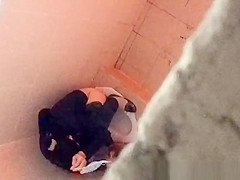 Asian woman spied over the toilet wall taking a pee