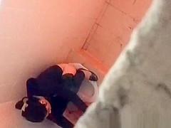 Asian woman spied over the toilet wall taking a pee