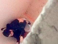 Asian woman spied over the toilet wall taking a pee