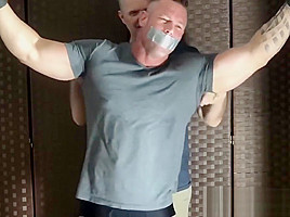 Bound muscular dude endures tickling from a mature deviant