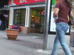 Hot body girl in tight jeans walking the street with a behind her
