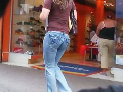 Hot body girl in tight jeans walking the street with a behind her
