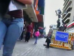 Hot body girl in tight jeans walking the street with a behind her